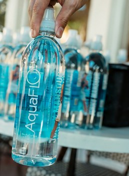 A hand picking an AquaFlo bottle from a table of bottles